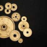 Close-up of gold gears arranged on a black backdrop, symbolizing teamwork and technology.
